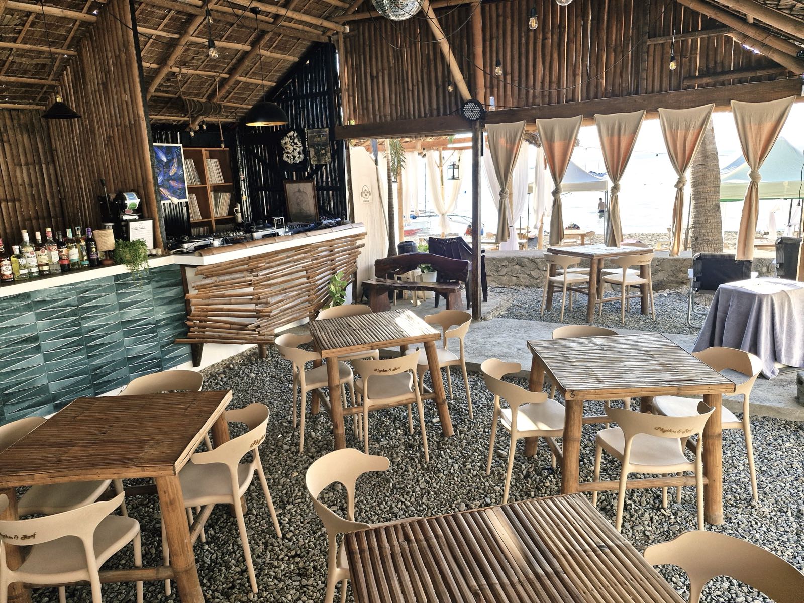 Communal dining under string lights at dusk by the beach