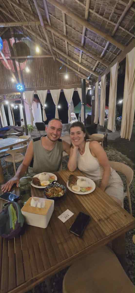 A couple dining together in the evening under string lights and draped curtains
