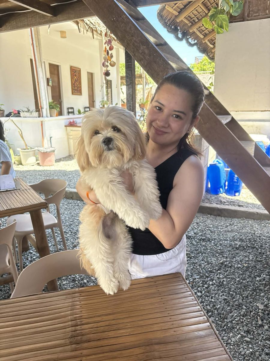 A guest smiling on the terrace with her small white dog in her arms