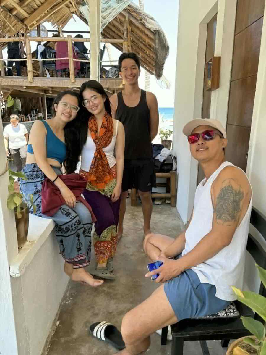 Four guests relaxing together on the shaded beachside terrace